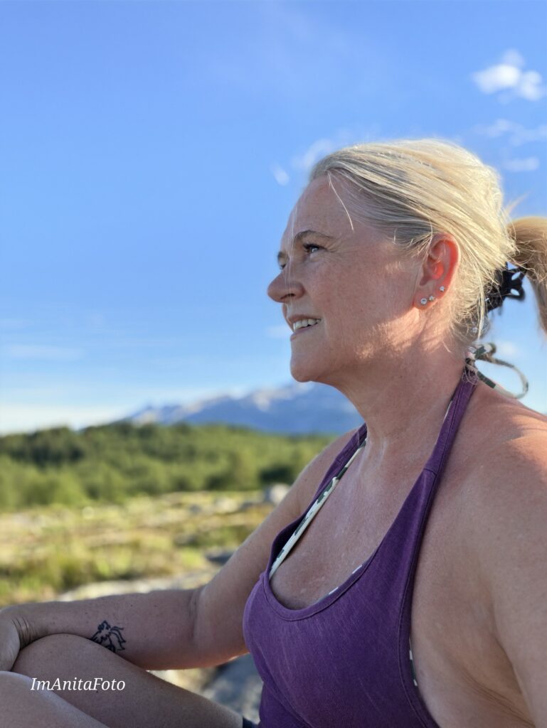 Anita Sofie Hauknes i Imanita AS ute i landskapet på Helgeland med fjell i bakgrunnen